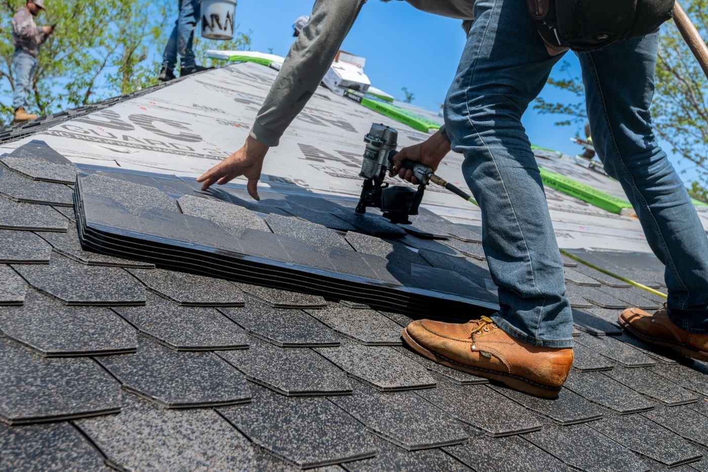 Close-up of a roofer using a nail gun to install shingles